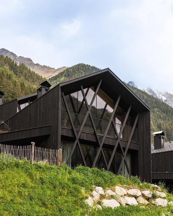 Chalet mit Wald und Bergen im Hintergrund.