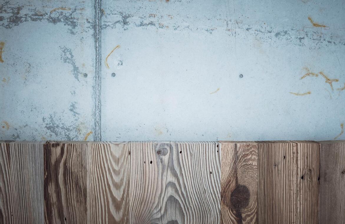 Detailansicht von Holz mit markanter Maserung am Übergang zu einer grauen Betonfläche.
