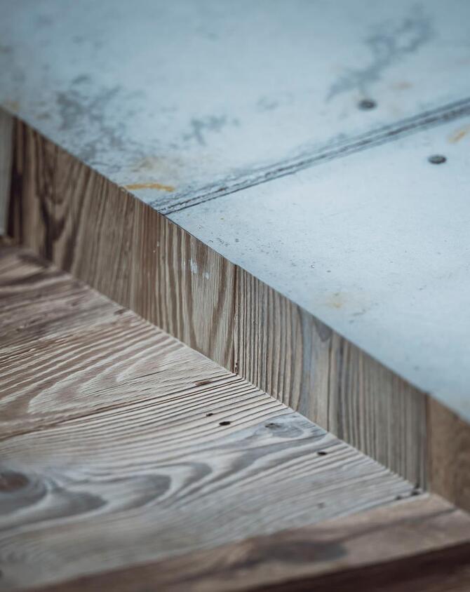 Detailansicht von Holz mit markanter Maserung am Übergang zu einer grauen Betonfläche.