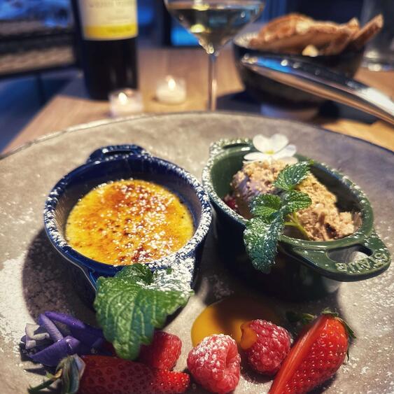 Dessert plate with ice cream, crème brûlée and fruit on a wooden table.