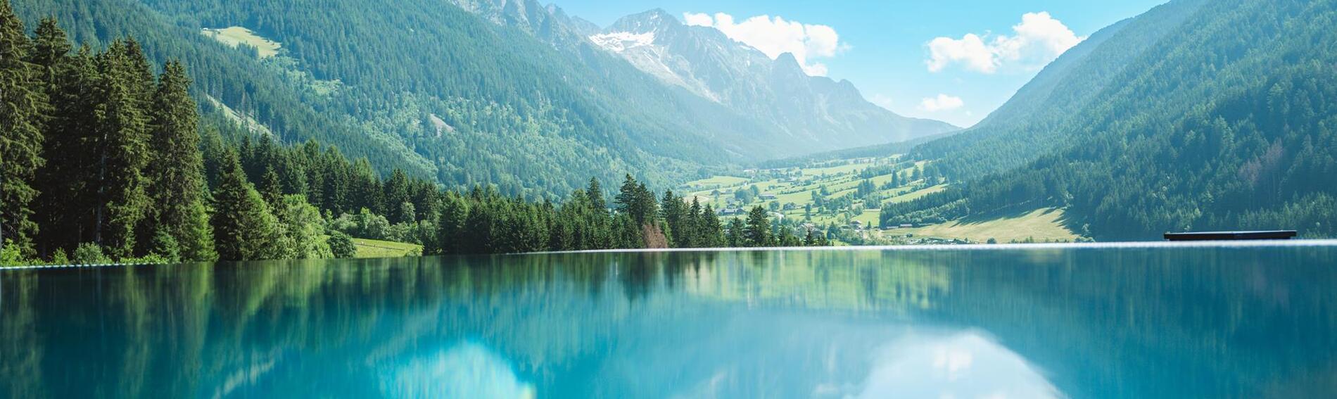 Blick vom Infinity-Pool aus auf die umliegenden Wiesen, Wälder und Berge.