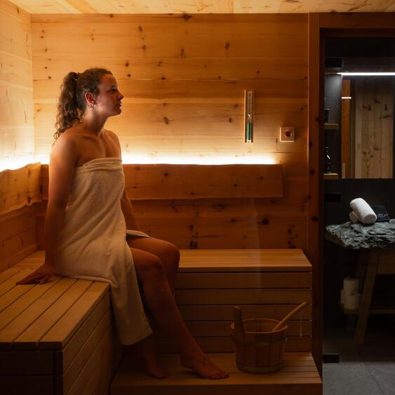 Frau sitz auf der hellen Holzbank in der Sauna.
