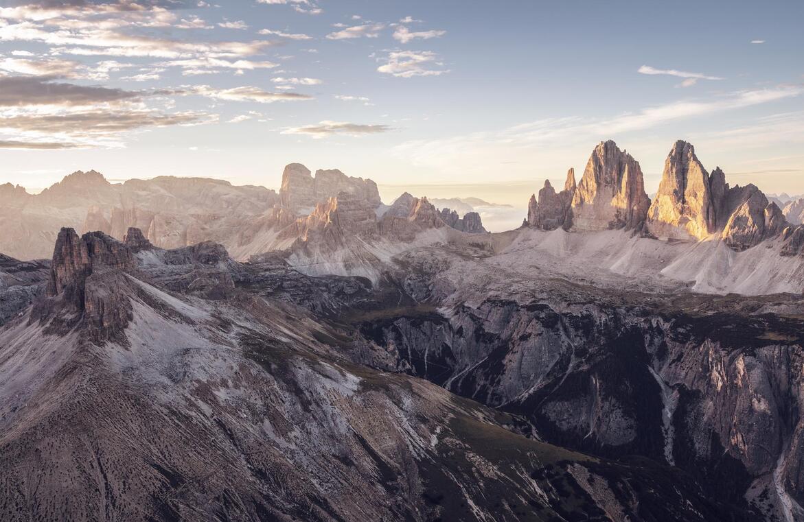 Vista sulle Tre Cime di Lavaredo all'alba, circondate dal caratteristico paesaggio dolomitico.