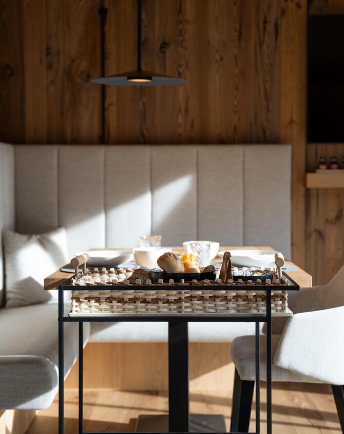 Frühstückswagen vor einem gedeckten Holztisch mit weißen Schalen im Amus Chalet.